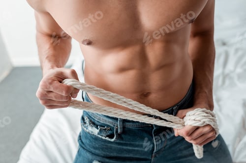 Preview: cropped view of dominant man in jeans holding rope
