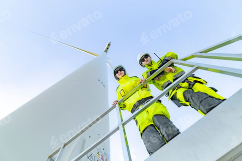 Preview: engineers in safety gear work on a wind farm