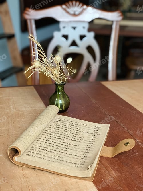 Preview: An inventory of wines catalogued in a book leather sitting on a table with a vase of dried flowers