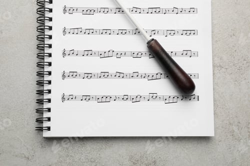 Preview: Conductor's baton and sheet music book on grey background