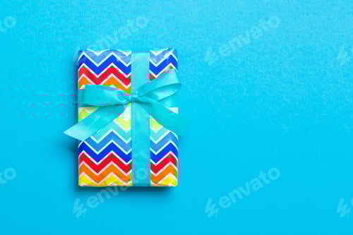 Preview: Gift box with blue bow for Christmas or New Year day on blue background, top view with copy space