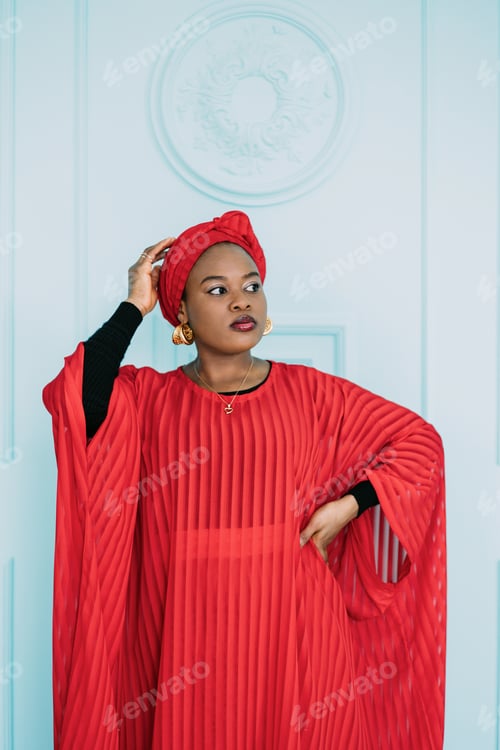 Preview: Portrait of an attractive african woman looking away on the blue wall background. Woman in red