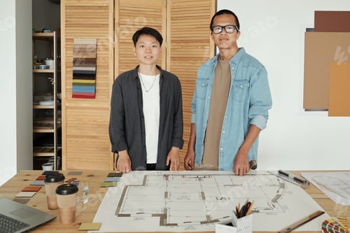 Preview: Two young successful engineers standing by workplace