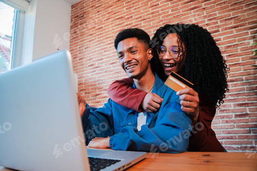 Preview: A cheerful African American couple is using a laptop to search a sale on a online shop. Excited
