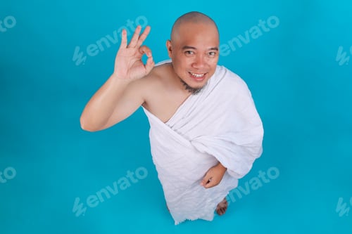 Preview: High Angle View of Happy Asian Muslim Man in Ihram Clothes Showing OK Sign