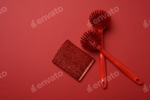 Preview: Two red plastic brushes and a sponge for washing dishes on a red background