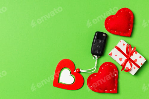 Preview: Top view of car key, gift boxes and toy hearts on colorful background.