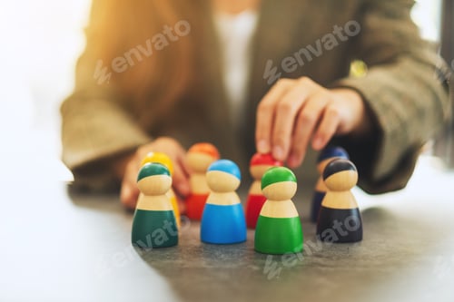 Preview: Businesswoman leader choosing wooden people figure from a group of employees in office