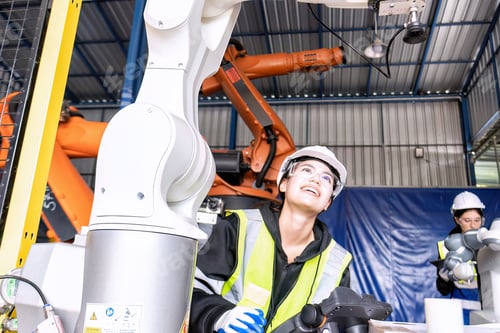 Preview: Young female asian service engineer holding robot controller operate robot arm automation factory