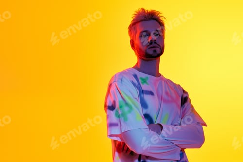 Preview: Handsome young man stands confidently in front of a vibrant yellow backdrop