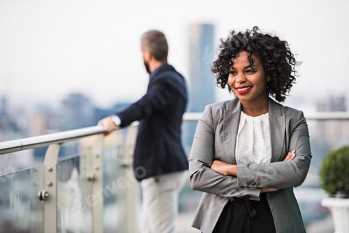 Preview: A portrait of a businesswoman standing on a terrace, arms crossed.