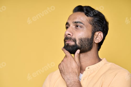 Preview: Thoughtful doubtful indian man thinking isolated on yellow. Portrait