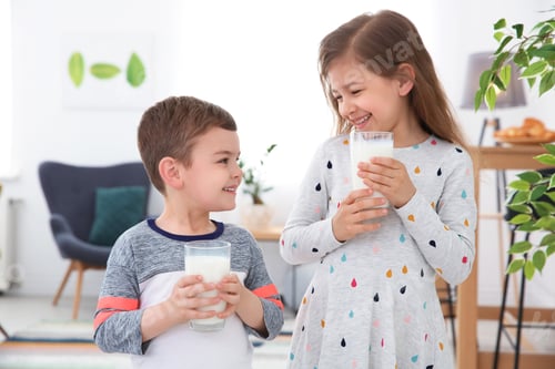 Preview: Cute little kids with glasses of milk indoors
