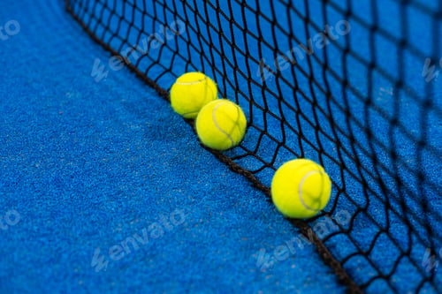 Preview: balls near the net of a blue padel tennis court