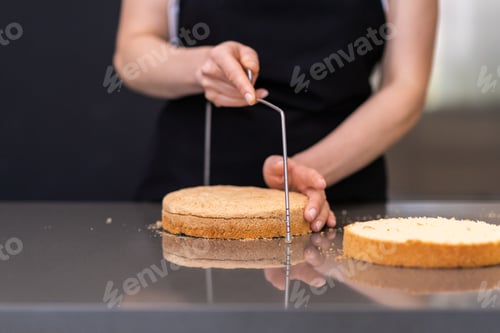 Preview: Skilled woman using string knife for separating cake layers in modern kitchen