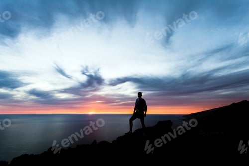 Preview: Celebrating or meditating man looking at sunset ocean