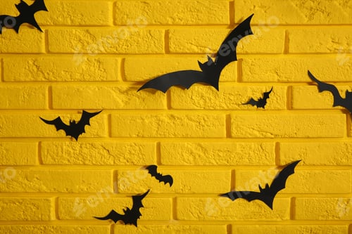 Preview: Yellow brick wall decorated for Halloween with paper bats