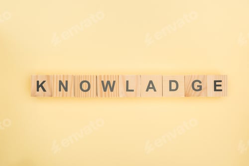 Preview: top view of knowledge lettering with mistake made of wooden cubes on yellow background
