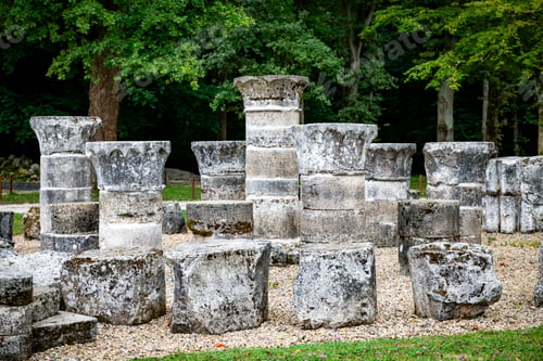 Preview: Ancient Stone Columns in Outdoor Ruins Surrounded by Green Trees and Gravel Ground