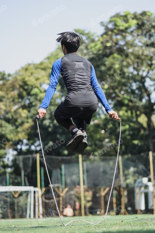 Preview: Back view of sportsman jumping with skipping rope