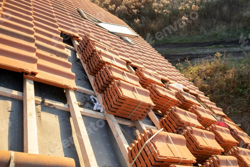 Preview: Stacks of yellow ceramic roofing tiles for covering residential building roof under construction