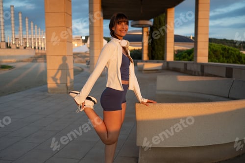 Preview: Woman stretching leg outdoors at sunset in Barcelona