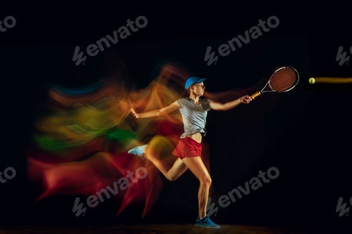 Preview: One caucasian woman playing tennis on black background in mixed light