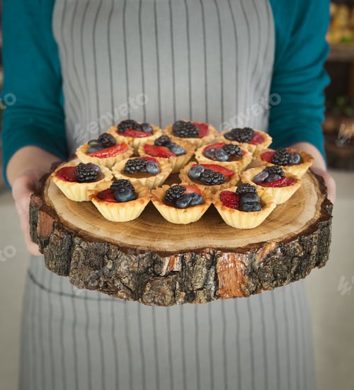Fresh Berry Tarts Held on Wooden Cutting Board
