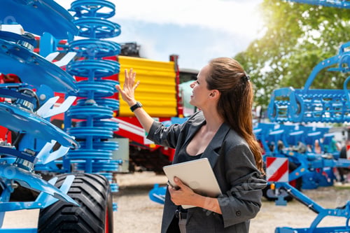 Preview: Woman sales representative at dealership presenting farm tools to client farmer