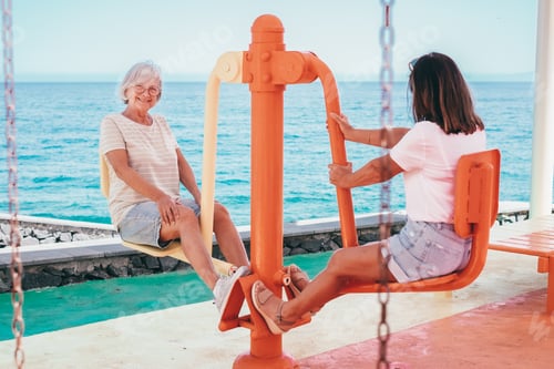 Preview: Smiling Senior Women Have Fun Doing Exercises in Public Open Air Gym Equipment to Stay fit