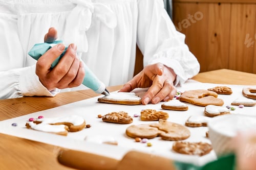 Preview: Woman decorating heart shaped cookies with frosting.