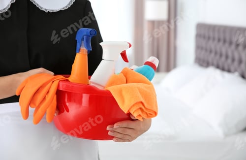 Preview: Young chambermaid with cleaning supplies in bedroom, closeup. Space for text