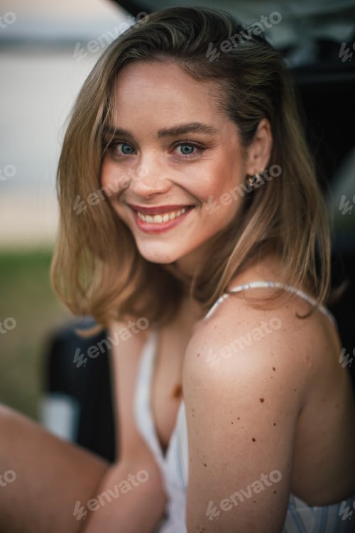 Preview: Portrait of beautiful woman sitting in a car trunk.