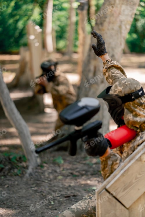 Preview: in the wild near tree structures player in a pintball uniform holds a pistol with a balloon team