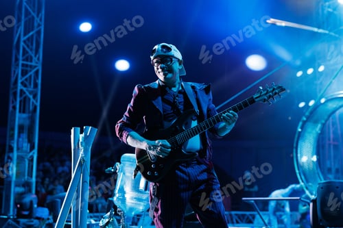 Preview: Clown entertains guests in the circus arena in the light of spotlights and smoke, plays the guitar.
