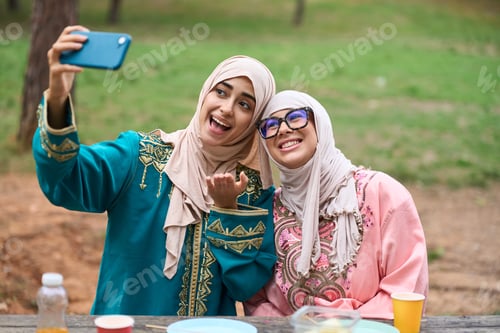 Preview: Muslim women friends taking selfie during picnic