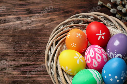 Preview: Colorful Easter eggs in decorative nest on wooden background, closeup. Space for text