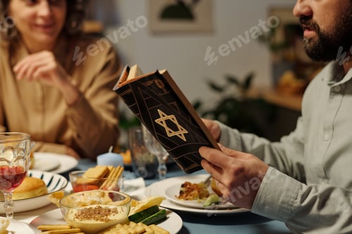 Preview: Bearded Jewish man reading text from Torah by served table