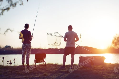 Preview: Young man fishing on a lake at sunset and enjoying hobby