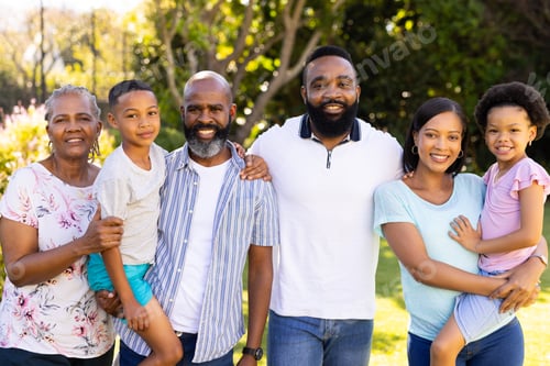 Preview: Standing together and smiling, multi-generational family in sunny garden outdoors