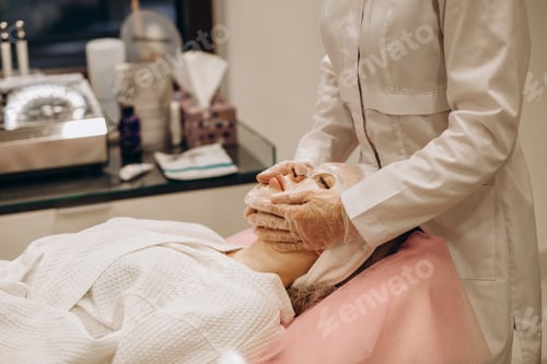 Preview: Cosmetologist applying mask on woman's face in spa salon, top view. Space for text