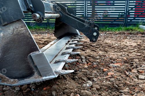 Preview: A backhoe loader carries and levels rubble on a dirt road.