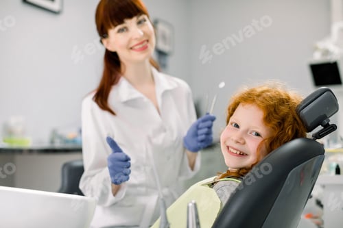 Side view of cheerful Caucasain girl with curly red hair, lying on dentist chair