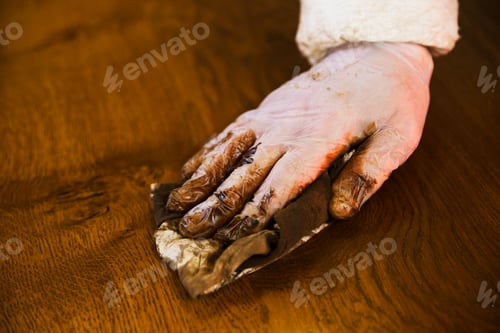 Preview: Carpenter wapplying varnish onto a wooden surface with a cloth.