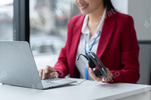 Preview: Asian businesswoman employee or executive using laptop computer and holding video headset explaining