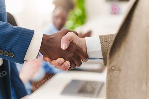 Preview: Close-up of a multiracial handshake in a formal office setting.