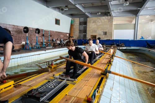 Preview: Competitive disciplined swimmers take positions on row simulator in pool preparing for championship