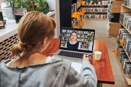 Preview: Student learning in university library. Young woman having video class listening to online course