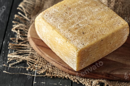 Vista previa: Quality cheese block on a wooden board with rustic texture and burlap backdrop