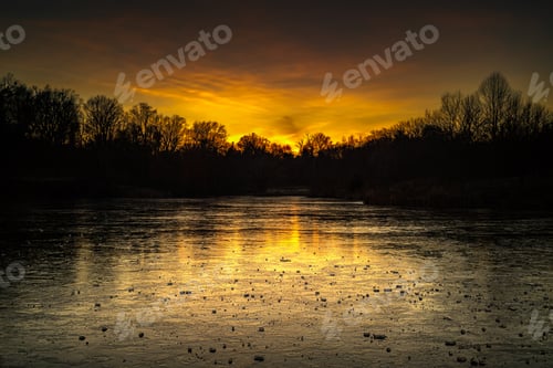 Preview: Gorgeous view of the Cherokee Lake during sunset with a frozen surface surrounded by dark trees